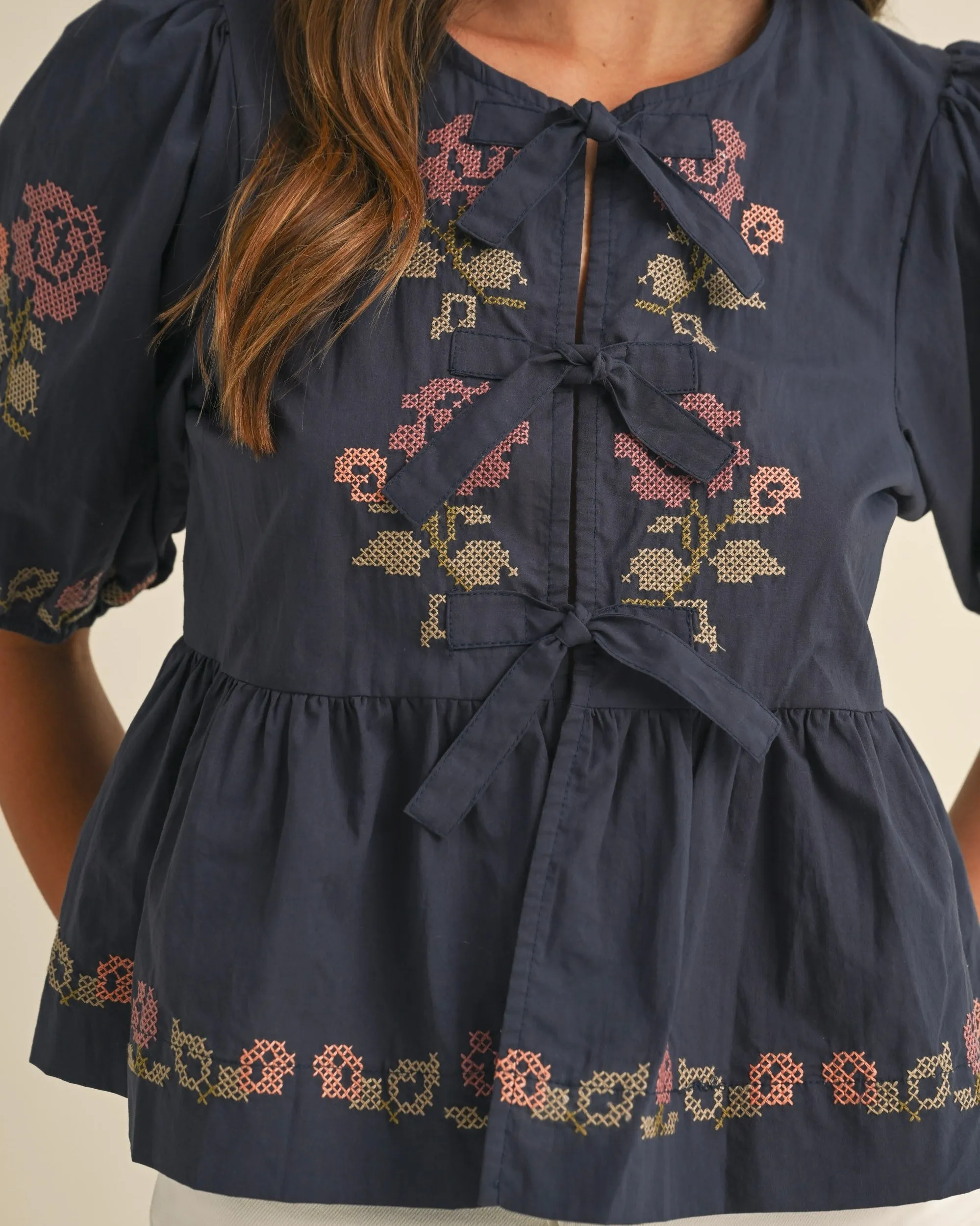 Embroidered Puff Sleeve Bottom Ruffle Front Tie Top in Navy